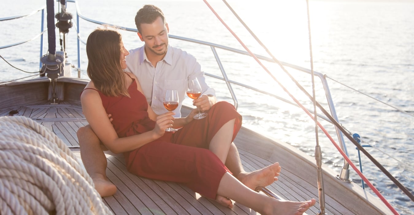 A couple enjoying a glass of wine while sailing on the lake.