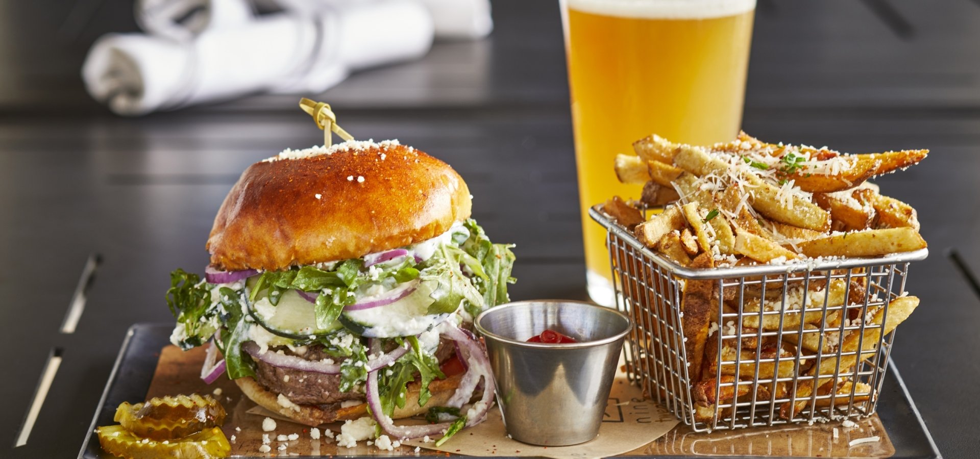 A burger, basket of fries and a beer