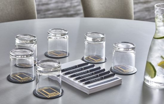 Meeting room table set with glasses, notepads and pens