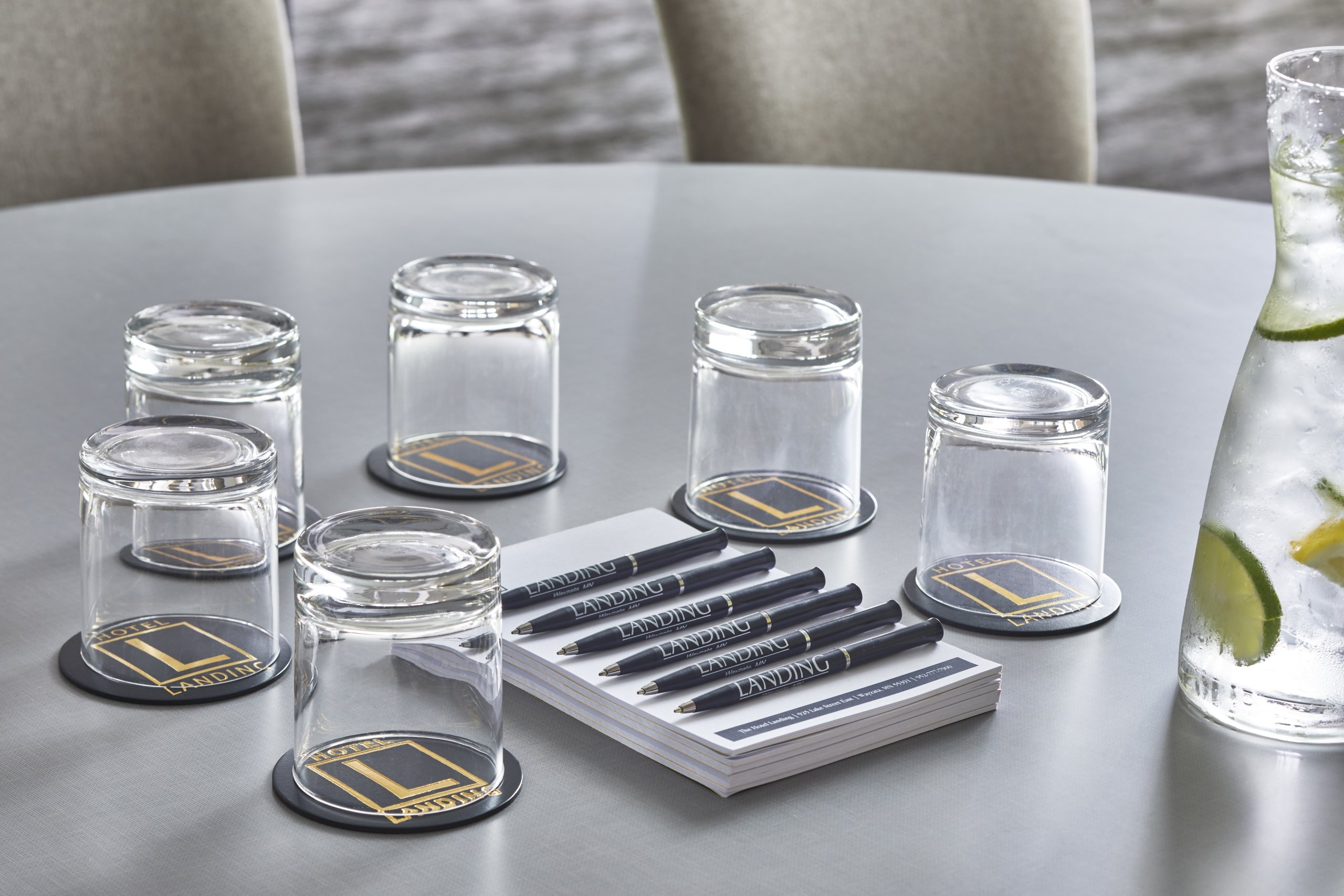 Meeting room table set with glasses, notepads and pens