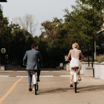 Bride and groom on bikes riding down the road