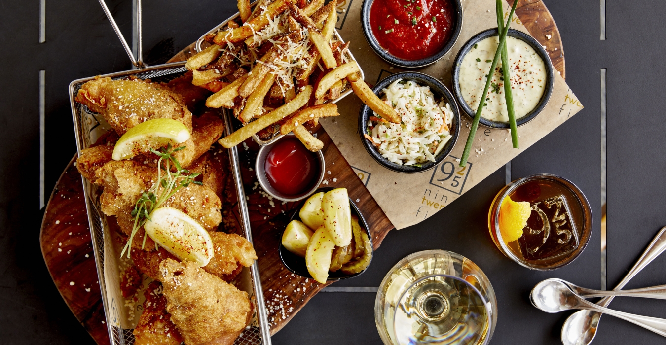Fried fish served with side of fries and cocktail set on dinner table