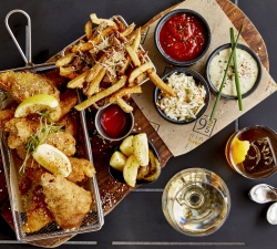 Fried fish served with side of fries and cocktail set on dinner table
