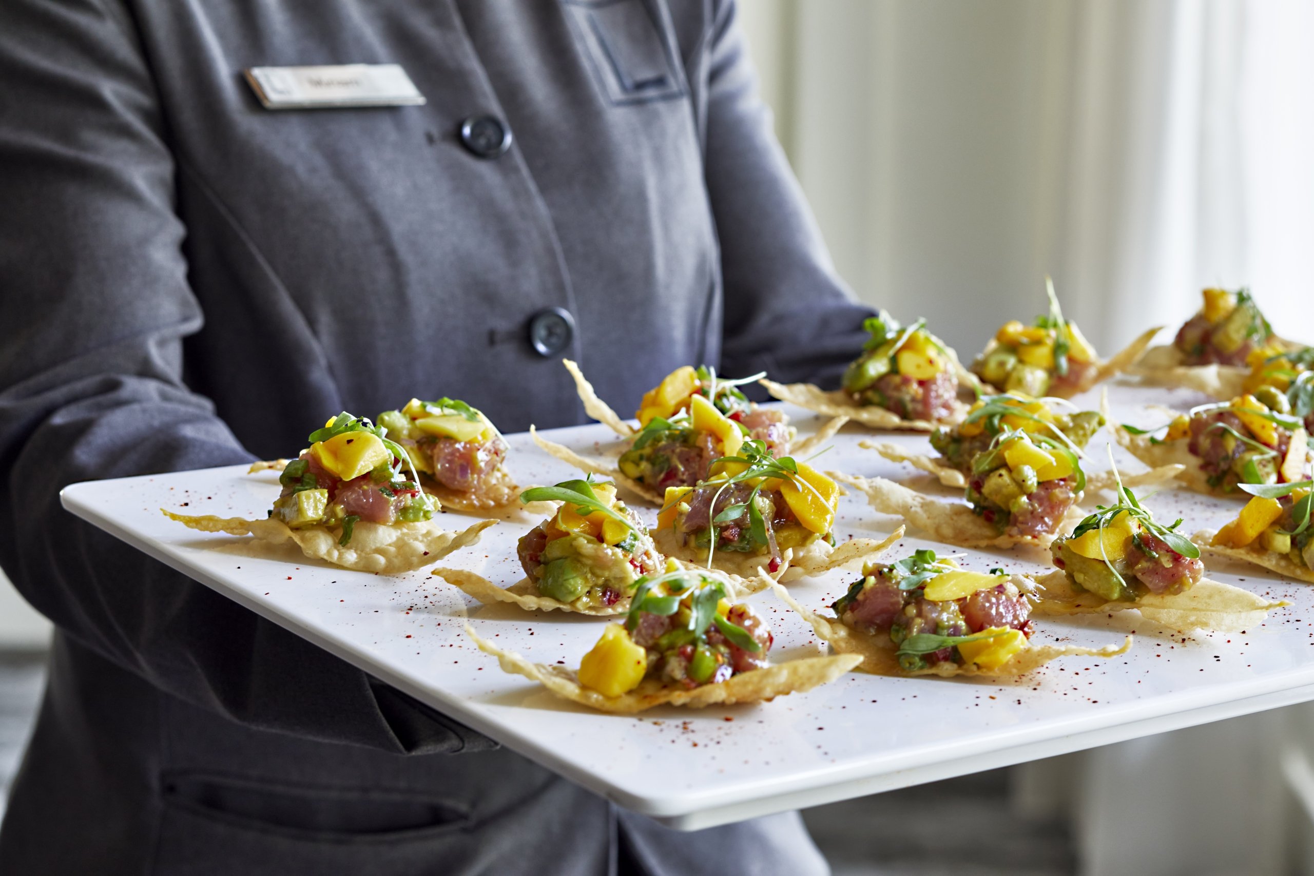 Server holding a plate of passed hors d'oeuvres