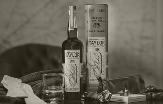 WIth a Sepia filter, a 750 milliliter bottle of Colonel E.H. Taylor Single Barrel Bourbon Whiskey with the case it is manufactured in at a customer's home