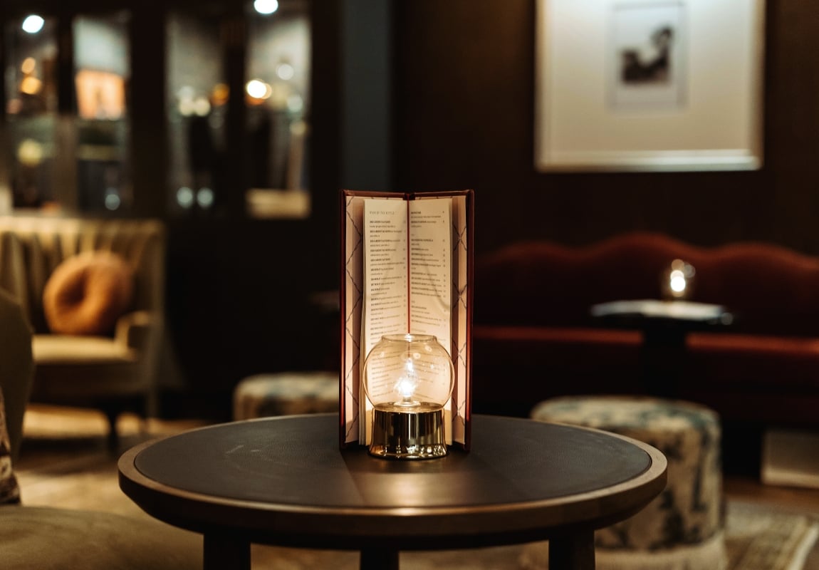 Menu card stand on a table in a dim, candlelit restaurant setting with a glowing bulb nearby.